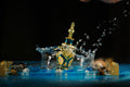 A teal and gold designer bottle of Liquid Luck Attar by Perfumous splashing in water, representing a fresh surge of success.